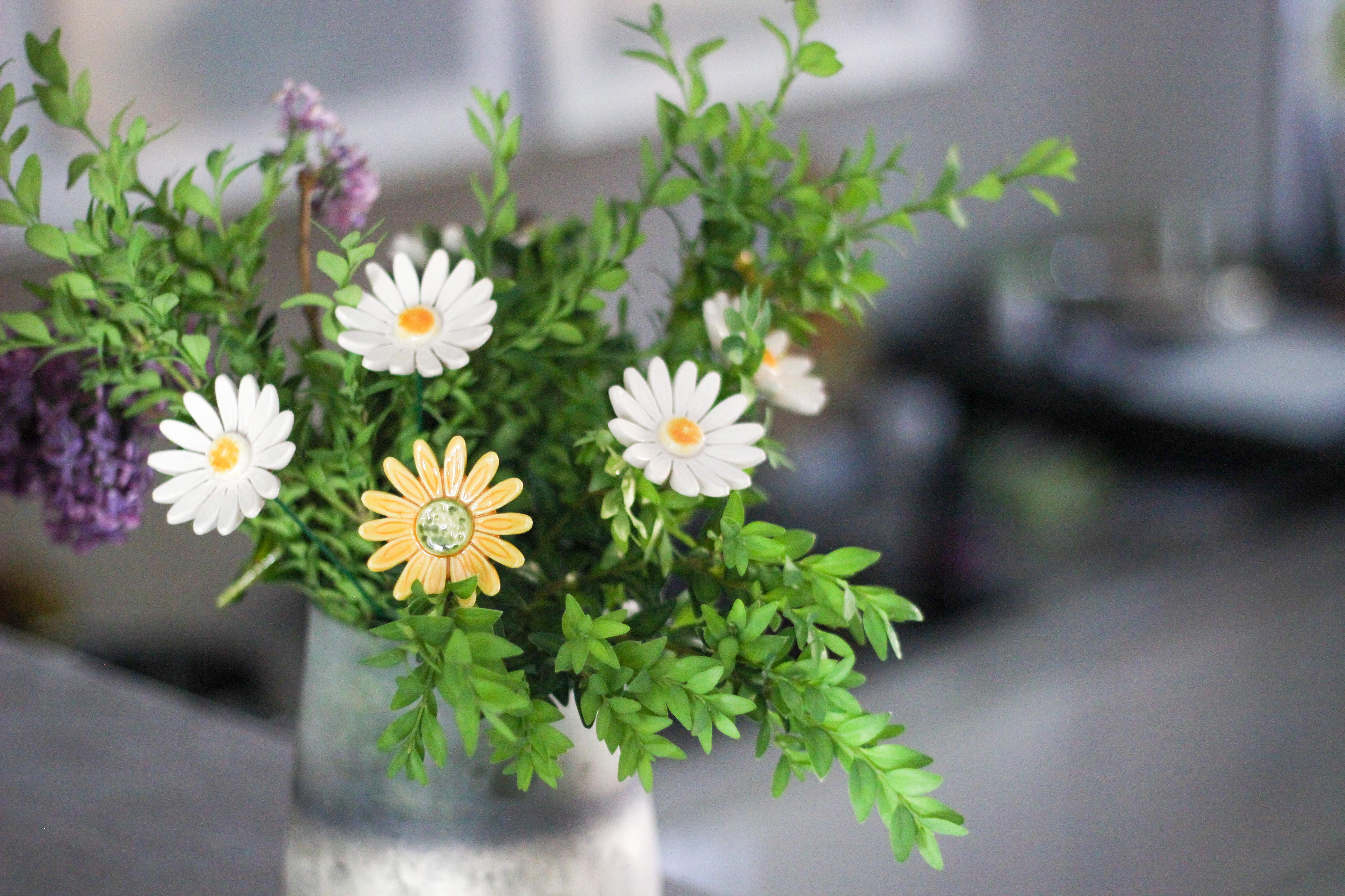 keramisches Gänseblümchen und Grünpflanzenkomposition